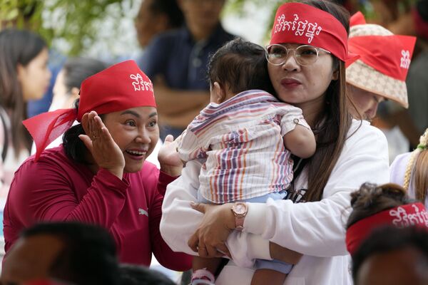 Una mujer juega con un niño mientras asisten a una celebración del 8M en Camboya. En las bandanas se lee &quot;Vida digna&quot;. - Sputnik Mundo