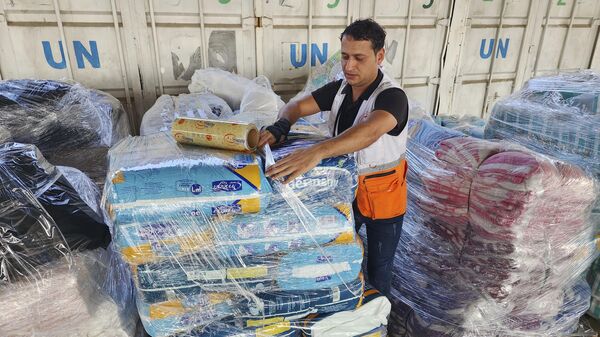 Un trabajador de Naciones Unidas prepara la ayuda para su distribución a los palestinos  - Sputnik Mundo