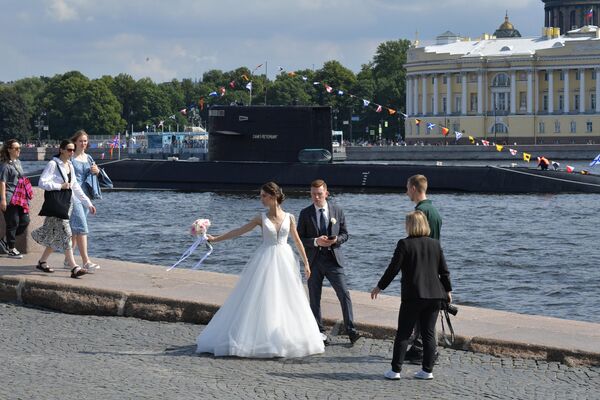 Recién casados en el paseo marítimo de San Petersburgo.Al fondo: submarino diésel-eléctrico B-585 Sankt Peterburg en aguas del río Neva tras un ensayo del desfile naval por el Día de la Armada. - Sputnik Mundo