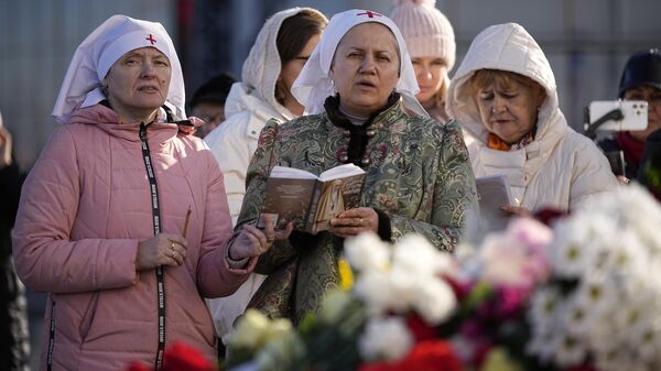 Mujeres rezan cerca del Ayuntamiento de Crocus en el extremo occidental de Moscú, Rusia, el lunes 25 de marzo de 2024, tras el ataque a la sala de conciertos Crocus City Call  - Sputnik Mundo