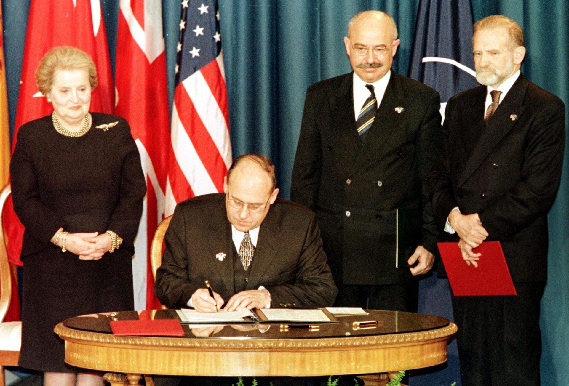 El ministro de Exteriores checo, Jan Kavan (sentado), firma el documento de adhesión de la República Checa a la OTAN el 12 de marzo de 1999 en la Biblioteca de Harry Truman, en Missouri, EEUU. De pie, la secretaria de Estado norteamericana Madeleine Albright (izquierda), el ministro de Exteriores húngaro, János Martonyi (centro), y el ministro de Exteriores polaco Bronislaw Geremek (derecha). - Sputnik Mundo, 1920, 29.03.2024
