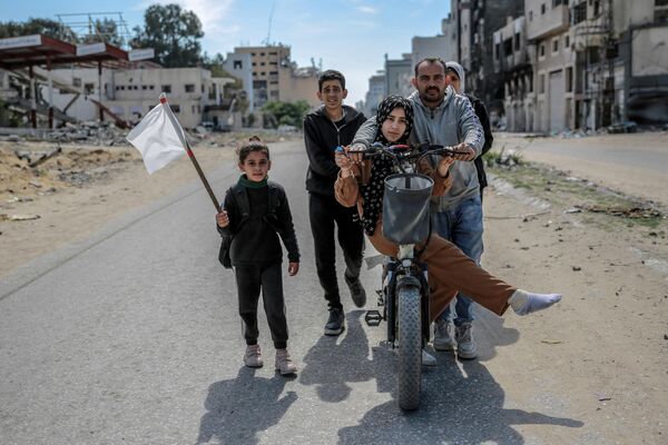 Una niña sostiene una bandera blanca mientras su familia desplazada camina en la ciudad de Gaza. Israel lanzó ataques masivos contra Gaza, después de que el movimiento palestino Hamás atacara al primero desde territorio gazatí el 7 de octubre de 2023. - Sputnik Mundo