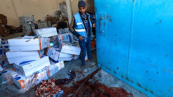 Un trabajador de la ONU cerca de un charco de sangre en un almacén y centro de distribución de la UNRWA en Rafah, en el sur de la Franja de Gaza, luego de un ataque israelí el 13 de marzo de 2024 - Sputnik Mundo