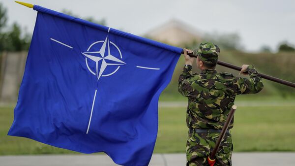 Un militar rumano enarbola la bandera de la OTAN tras la visita del ministro de Defensa británico, Michael Fallon, a una base aérea en Rumania, el 14 de junio de 2017 - Sputnik Mundo
