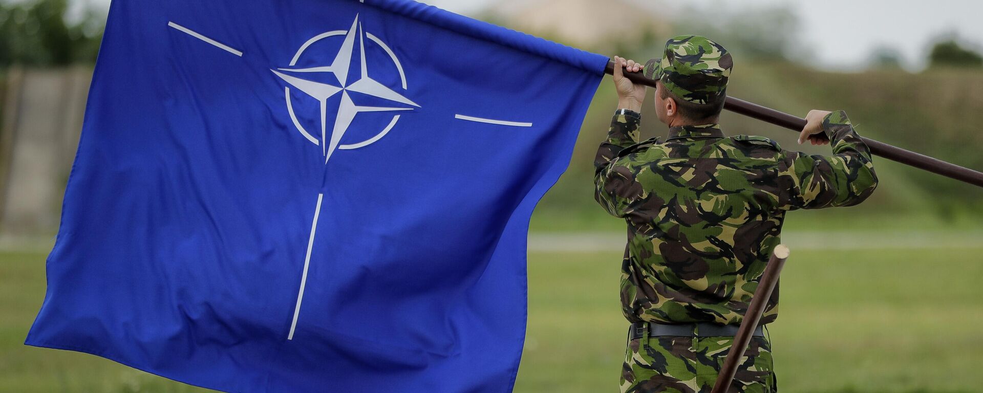 Un militar rumano enarbola la bandera de la OTAN tras la visita del ministro de Defensa británico, Michael Fallon, a una base aérea en Rumania, el 14 de junio de 2017 - Sputnik Mundo, 1920, 09.05.2024