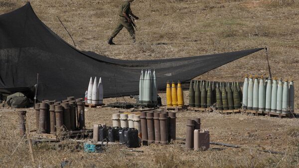 Un soldado israelí camina entre municiones 155 mm y otras más cerca de la frontera con el Líbano - Sputnik Mundo