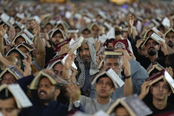 Fieles chiíes se ponen libros del Corán sobre la cabeza durante la Noche del Destino, en el sagrado mes de ayuno del Ramadán en el santuario del imán Musa al Qadim, en Bagdad. - Sputnik Mundo