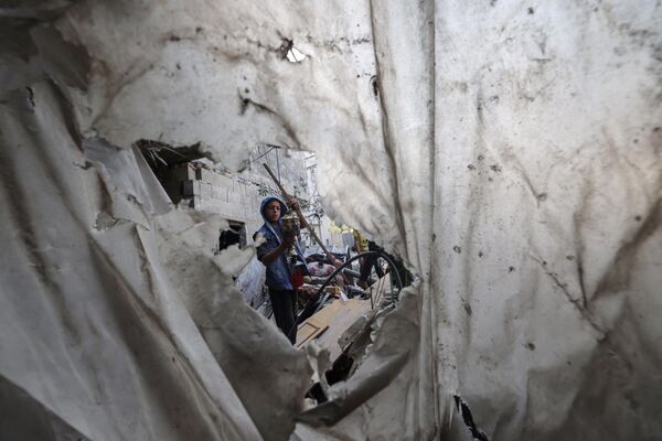 Un niño palestino busca objetos sobrevivientes entre los escombros de un piso destruido en Rafah, en el sur de la Franja de Gaza, tras un bombardeo israelí nocturno. - Sputnik Mundo