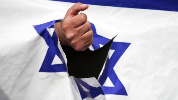 Un manifestante aprieta el puño a través de una representación rota de la bandera israelí en la manifestación anual propalestina del Día de Al Quds, o Jerusalén, en Teherán, Irán, el viernes 29 de abril de 2022. - Sputnik Mundo