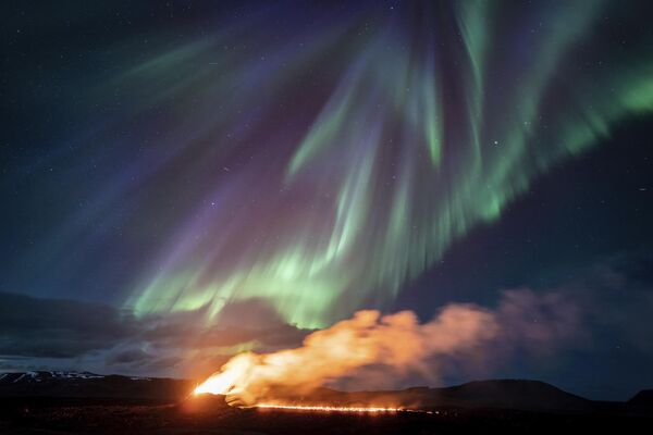 Vista de una zona de erupción con la aurora boreal en el cielo, en Islandia - Sputnik Mundo