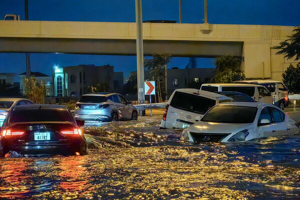Automóviles circulan por una calle inundada tras las fuertes lluvias en Dubái. - Sputnik Mundo