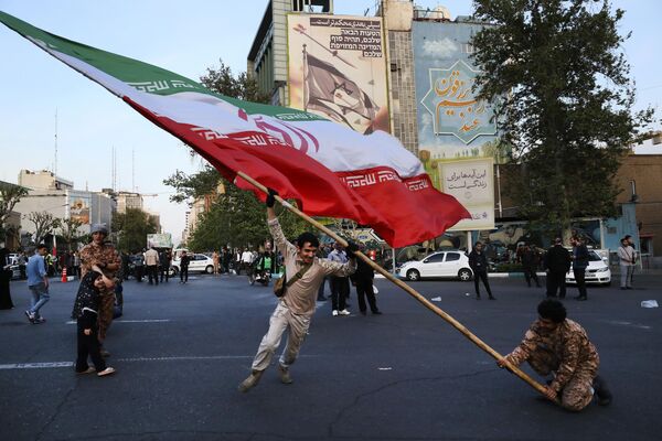 Manifestantes ondean una enorme bandera iraní en su concentración anti-israelí en Teherán, Irán. - Sputnik Mundo