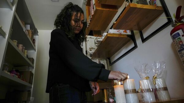 Una mujer enciende velas en su tienda tras un apagón programado ordenado por el Ministerio de Energía, en Quito, Ecuador - Sputnik Mundo