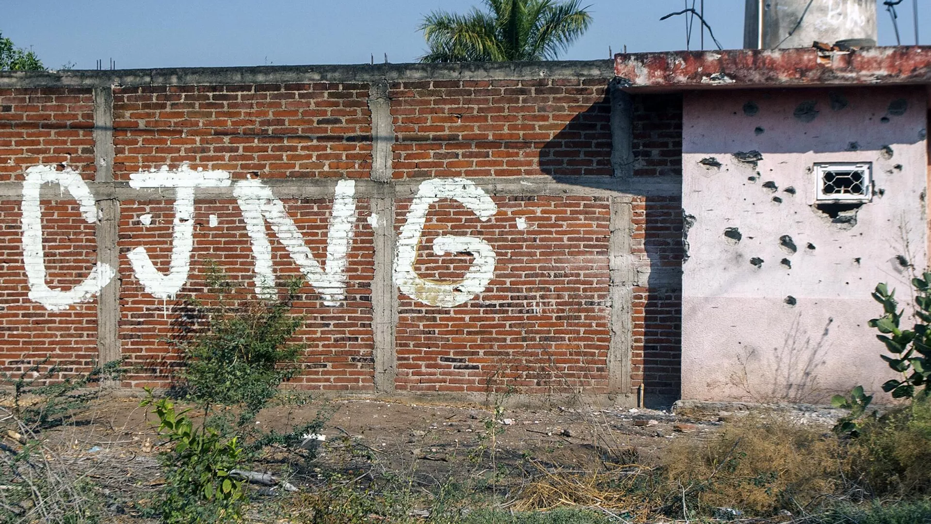 Vista de un muro acribillado a balazos con las iniciales del grupo criminal Cartel Jalisco Nueva Generación (CJNG) en la entrada de la comunidad de Aguililla, estado de Michoacán, México (archivo) - Sputnik Mundo, 1920, 23.04.2024