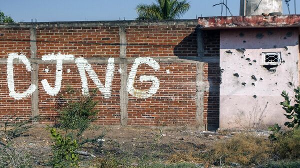 Vista de un muro acribillado a balazos con las iniciales del grupo criminal Cartel Jalisco Nueva Generación (CJNG) en la entrada de la comunidad de Aguililla, estado de Michoacán, México (archivo) - Sputnik Mundo