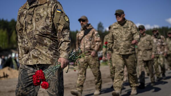 Soldados de la Defensa Territorial del Ejército Ucraniano sostienen flores para depositarlas en las tumbas de compañeros caídos, en el cementerio de Irpin, a las afueras de Kiev, el 1 de mayo de 2022  - Sputnik Mundo