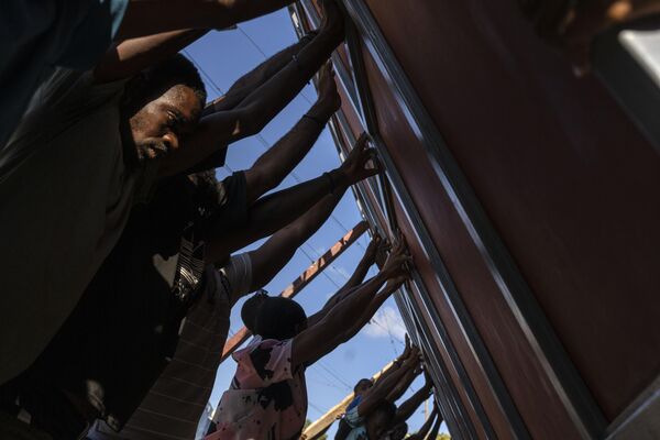 Las personas levantan una puerta metálica para instalarla como barricada contra las bandas, en el barrio Pétionville de Puerto Príncipe, Haití. - Sputnik Mundo