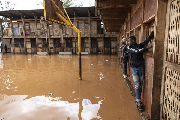 Residentes de la barriada de Mathare utilizan el muro para cruzar un campo escolar inundado, tras las fuertes lluvias en la capital keniana de Nairobi.  - Sputnik Mundo