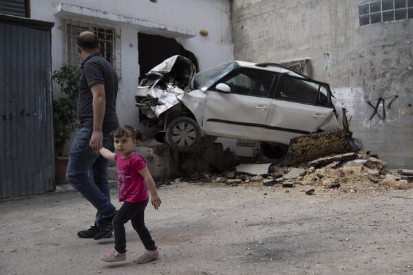 Palestinos inspeccionan un automóvil dañado en el campo de refugiados de Nur Shams en Cisjordania.  - Sputnik Mundo