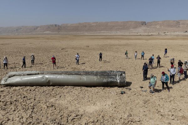 Las personas se reúnen alrededor de un componente de un misil balístico iraní que cayó cerca del mar Muerto en Israel. - Sputnik Mundo