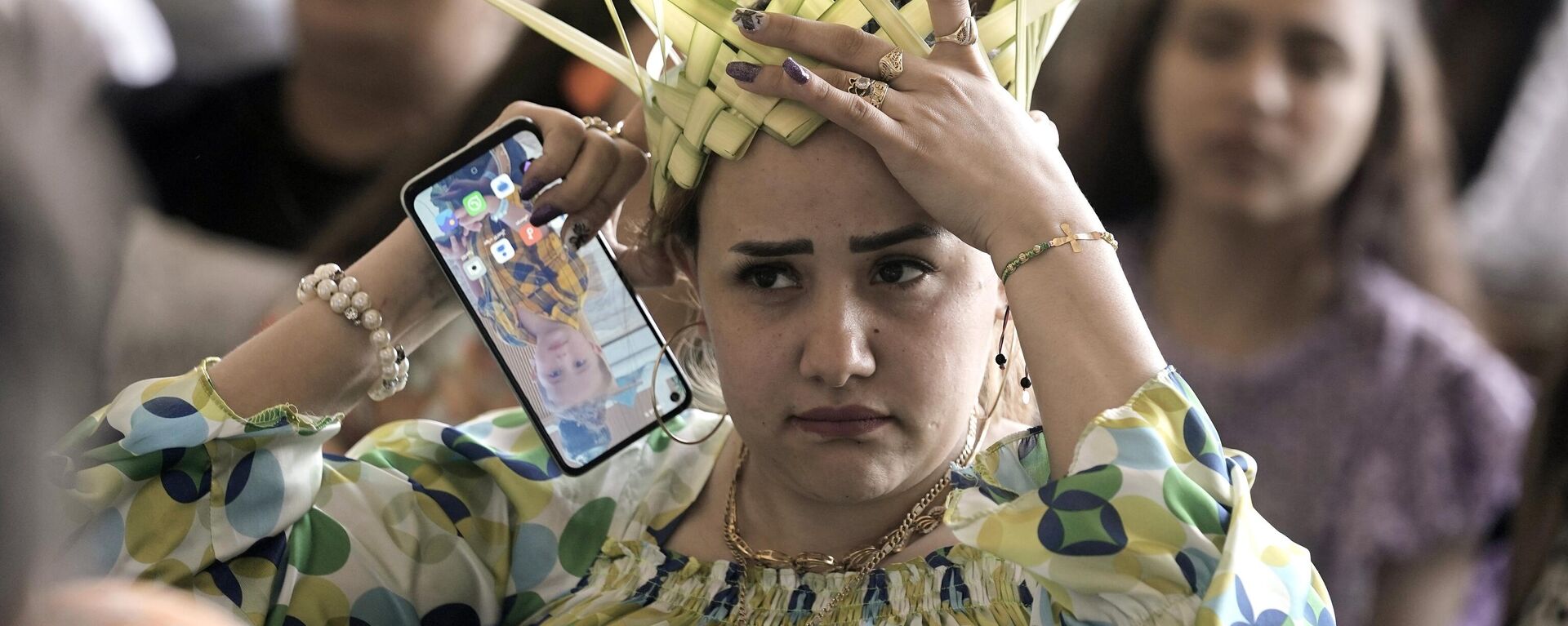 Una mujer cristiana copta ortodoxa ajusta su corona, hecha de hojas de palma, antes de rezar durante una misa de Domingo de Ramos en la capital egipcia de El Cairo. - Sputnik Mundo, 1920, 29.04.2024