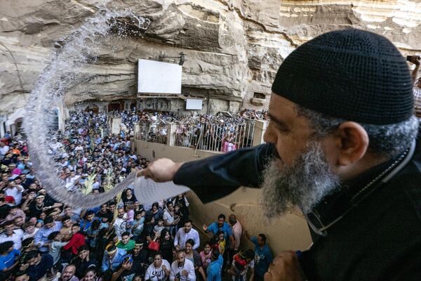 Un sacerdote copto ortodoxo rocía con agua bendita a los fieles durante el servicio del Domingo de Ramos en el Monasterio de San Simón el Curtidor, en El Cairo. - Sputnik Mundo