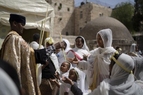 Un clérigo distribuye ramas de palma durante las celebraciones del Domingo de Ramos en la aldea etíope de Deir Al Sultan. - Sputnik Mundo