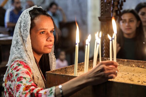 Una niña enciende una vela durante la misa del Domingo de Ramos en la iglesia de San Porfirio en Gaza. - Sputnik Mundo
