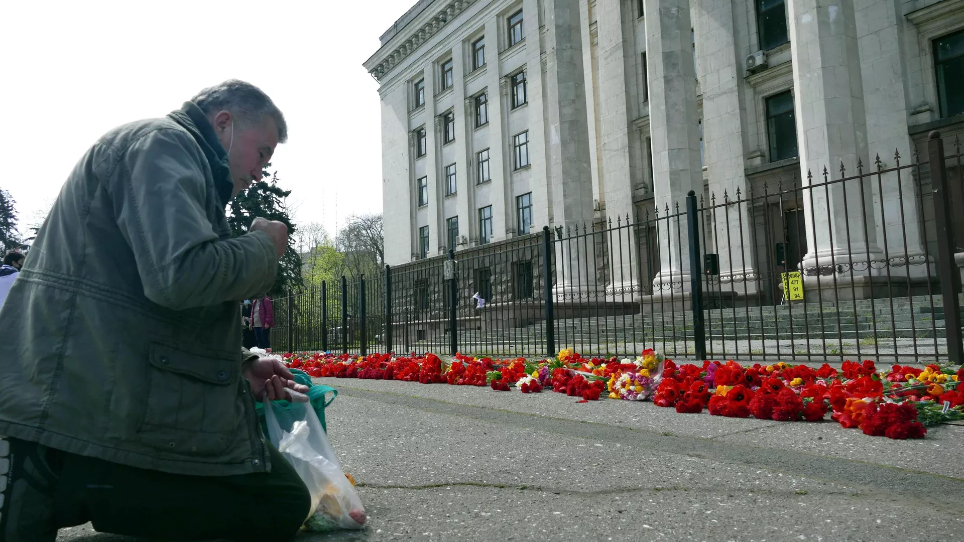 Un hombre recibe el bautismo de rodillas ante la Casa de los Sindicatos en Odesa para honrar la memoria de las víctimas en el aniversario de la tragedia - Sputnik Mundo, 1920, 02.05.2024