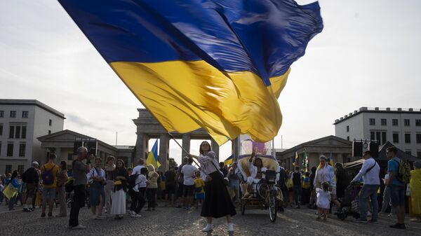 Una mujer ondea una enorme bandera ucraniana durante la manifestación para conmemorar el 32.° aniversario de la independencia de Ucrania en Berlín, Alemania, el 24 de agosto de 2023  - Sputnik Mundo