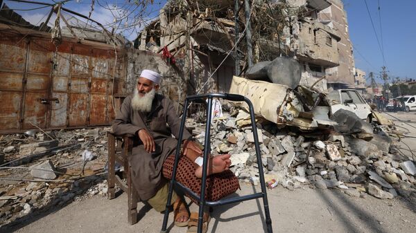 Un palestino sentado frente a un edificio dañado tras un bombardeo israelí en Rafah, en el sur de la Franja de Gaza, el 29 de abril de 2024. - Sputnik Mundo