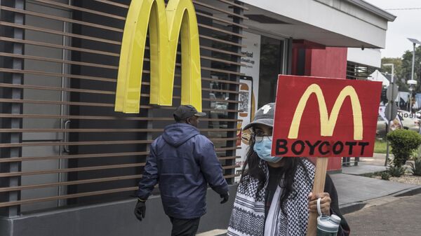 Un manifestante con una pancarta que pide boicotear la cadena de comida rápida McDonald's por su apoyo a Israel  - Sputnik Mundo