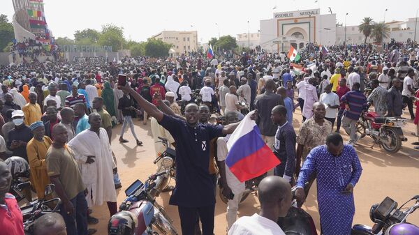 Partidarios de la junta gobernante de Níger sostienen una bandera rusa al comienzo de una protesta convocada para luchar por la libertad del país  - Sputnik Mundo