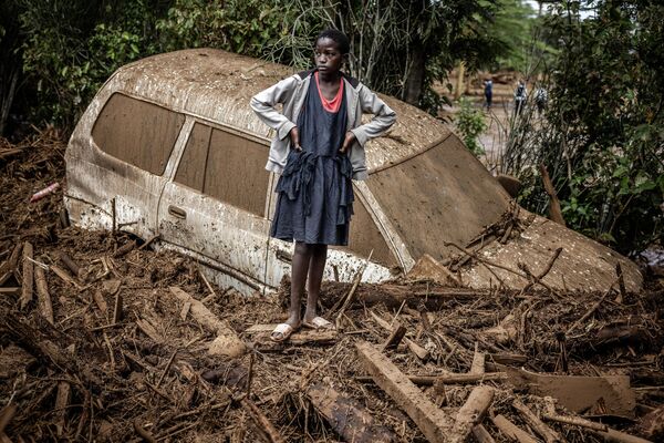 Una niña, junto a un automóvil dañado y hundido en el barro, en una zona muy afectada por las lluvias torrenciales e inundaciones repentinas en el pueblo de Kamuchiri, Kenia. - Sputnik Mundo