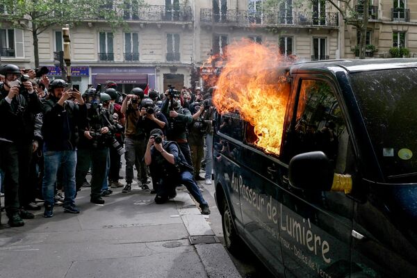 Reporteros sacan fotografías de un furgón incendiado al margen de la protesta anual que conmemora el Día Internacional de los Trabajadores en París. - Sputnik Mundo