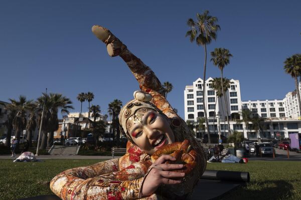 La contorsionista del Cirque du Soleil, Sender Enkhtur, comiendo una galleta mientras posa en la playa de Santa Mónica, California. - Sputnik Mundo