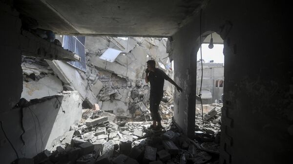 Palestinos observan la destrucción tras un ataque israelí contra un edificio residencial en Rafah, Franja de Gaza, el 7 de mayo, 2024 - Sputnik Mundo