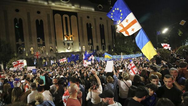 Manifestantes con banderas nacionales de Georgia y Ucrania y de la UE reunidos ante el edificio del Parlamento para protestar contra la ley sobre agentes extranjeros, el 28 de abril, 2024 - Sputnik Mundo