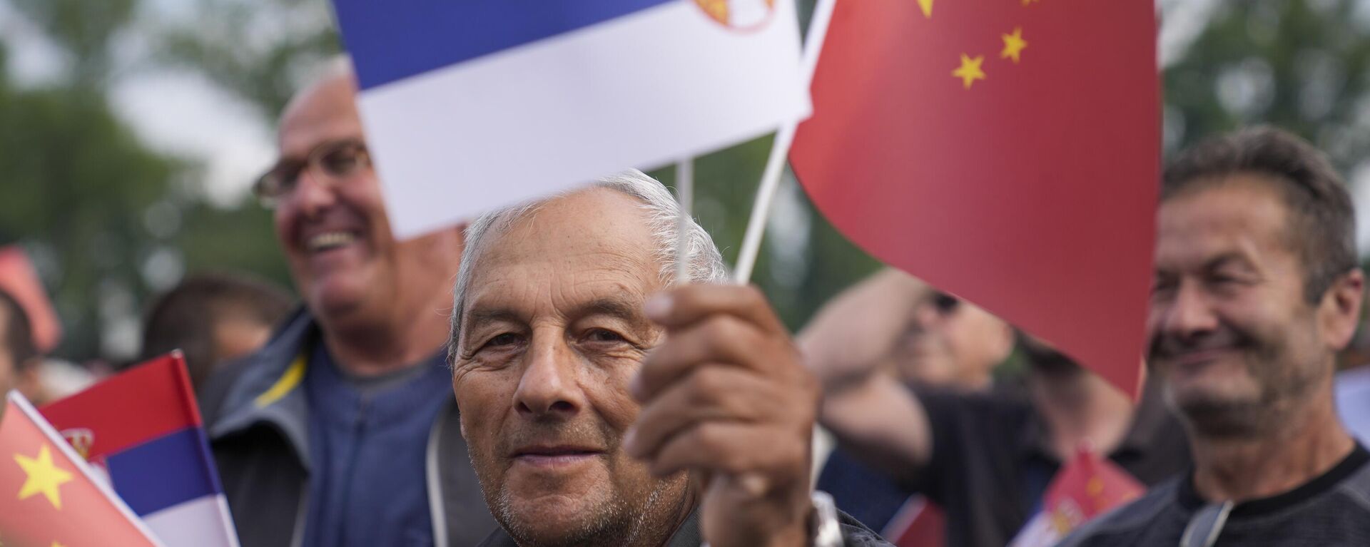 Un hombre ondea banderas chinas y serbias mientras espera la llegada del presidente chino Xi Jinping y su homólogo serbio Aleksandar Vucic a las puertas del Parlamento de Serbia. - Sputnik Mundo, 1920, 09.05.2024
