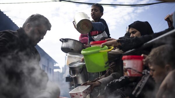 Palestinos hacen cola para recibir comida gratuita en Rafah, Franja de Gaza, el 16 de febrero de 2024  - Sputnik Mundo