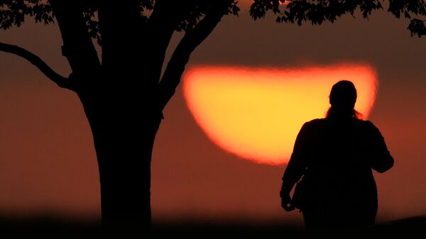 Una mujer observa la puesta de sol en un día caluroso, el 20 de agosto de 2023, en Kansas City, Missouri. Un nuevo estudio realizado el martes 14 de mayo de 2024 encuentra que el caluroso verano de 2023 fue el más caluroso en el hemisferio norte en más más de 2.000 años. (Foto AP/Charlie Riedel, archivo) - Sputnik Mundo