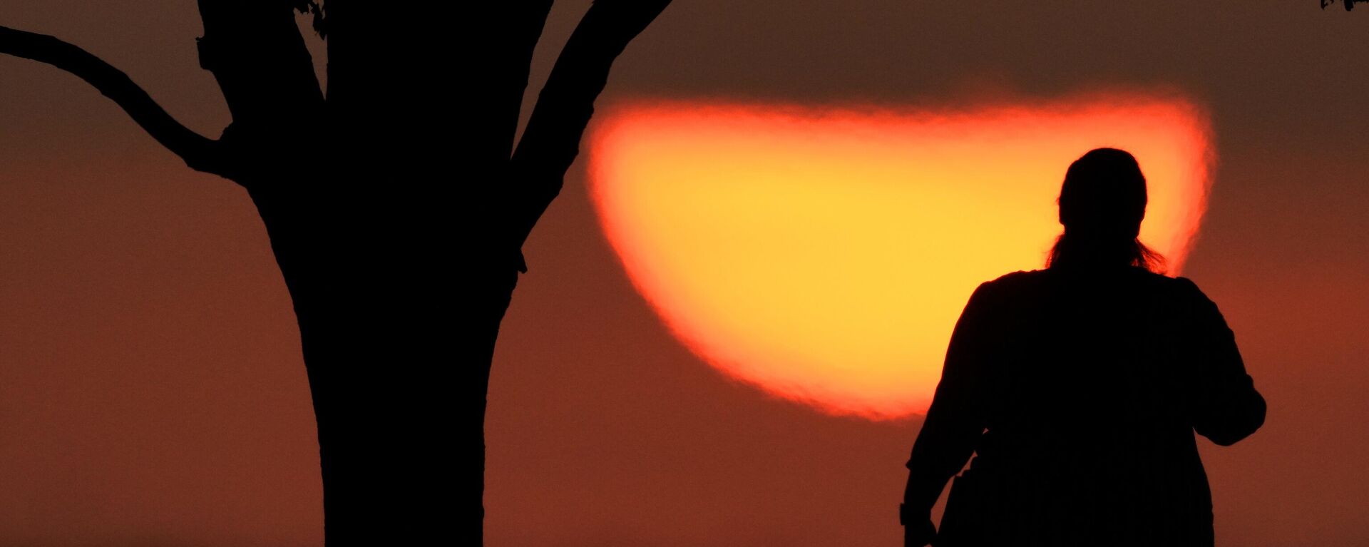 Una mujer observando la puesta de sol en un día caluroso, el 20 de agosto de 2023, en Kansas City, Missouri. Un nuevo estudio publicado el martes 14 de mayo de 2024 encuentra que el verano de 2023 fue el más caluroso en el hemisferio norte en más más de 2.000 años. (Foto AP/Charlie Riedel, archivo) - Sputnik Mundo, 1920, 14.05.2024