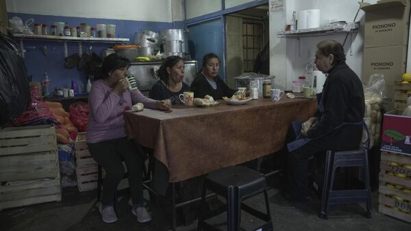 Los voluntarios comen antes de distribuir alimentos y servir comidas calientes en un comedor de beneficencia en Buenos Aires (archivo) - Sputnik Mundo