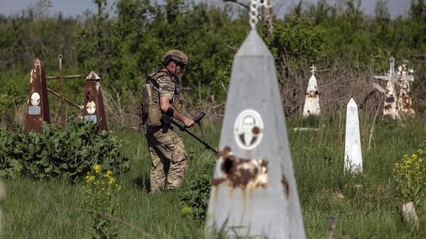 Un zapador ucraniano desmina un cementerio en Donetsk (archivo) - Sputnik Mundo
