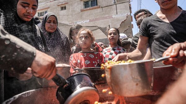 La gente se aglomera en un comedor público en la Franja de Gaza en medio del conflicto palestino-israelí - Sputnik Mundo
