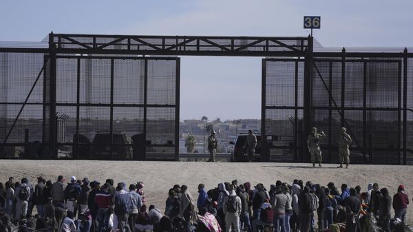 Migrantes que cruzaron la frontera de México hacia Estados Unidos esperan junto al muro fronterizo, donde hacen guardia agentes de la Patrulla Fronteriza (archivo)  - Sputnik Mundo