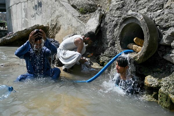 Un grupo de personas bañándose en un arroyo que recoge agua de una tubería dañada para refrescarse en un caluroso día de verano en Karachi, Pakistán. - Sputnik Mundo