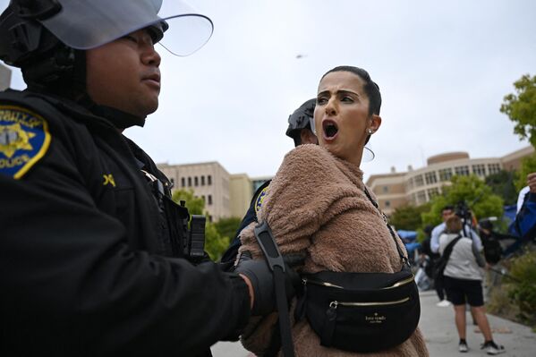Una manifestante pro-Palestina, detenida por la Policía durante el desalojo de una acampada que ocupaba el Aula de Ciencias Físicas de la Universidad de California. - Sputnik Mundo