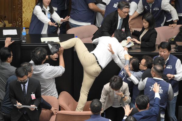 Un legislador del gobernante Partido Democrático Progresista de Taiwán Kuo Kuo Wen intenta saltar sobre el escaño durante la votación del proyecto de ley de reforma parlamentaria, en Taipéi. - Sputnik Mundo