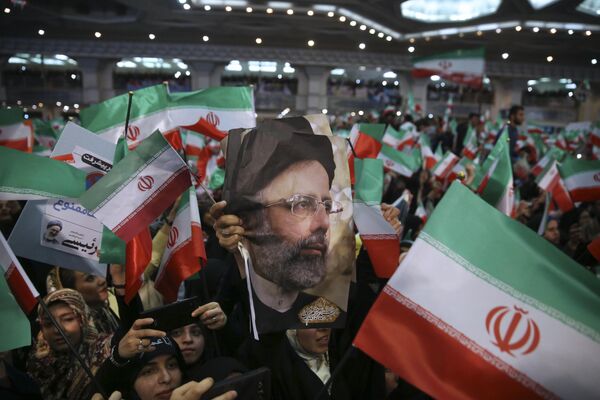 Partidarios de Raisi sostienen su foto y ondean la bandera iraní durante un mitin por las elecciones presidenciales de 2017 en Teherán, Irán, el 16 de mayo de 2017. - Sputnik Mundo